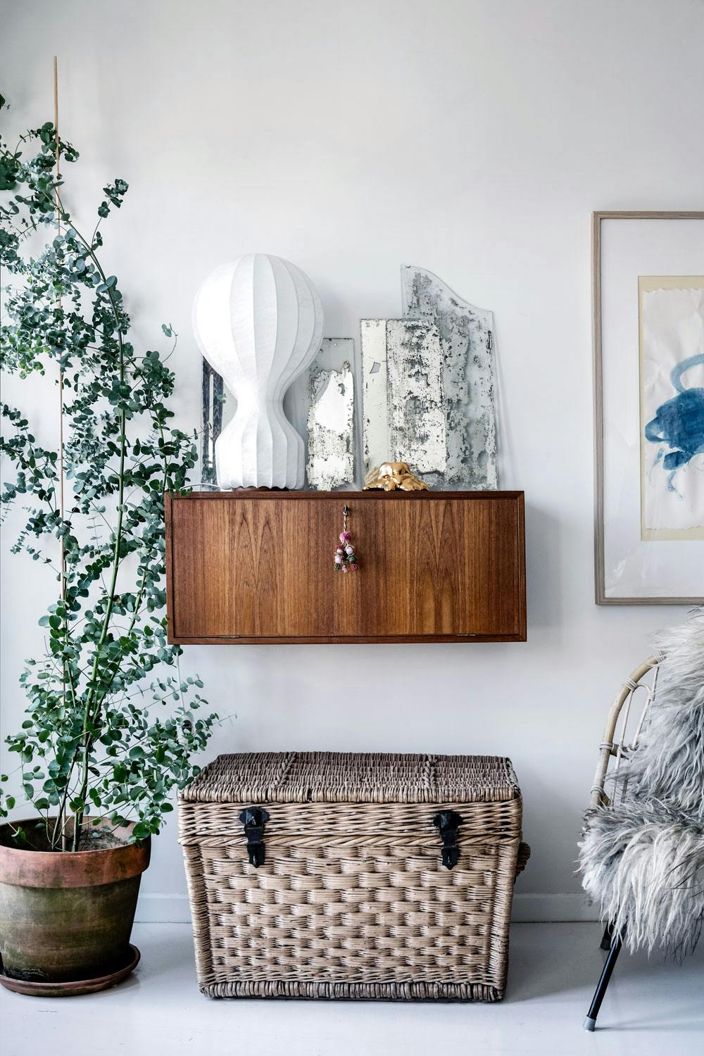 Sanselig lek med materialer Vegghengt teakskjenk med Gatto-lampen oppå og gamle vintage-speil